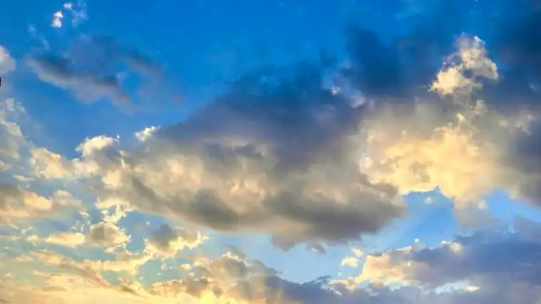 Sunset over lake with clouds and trees on the horizon.