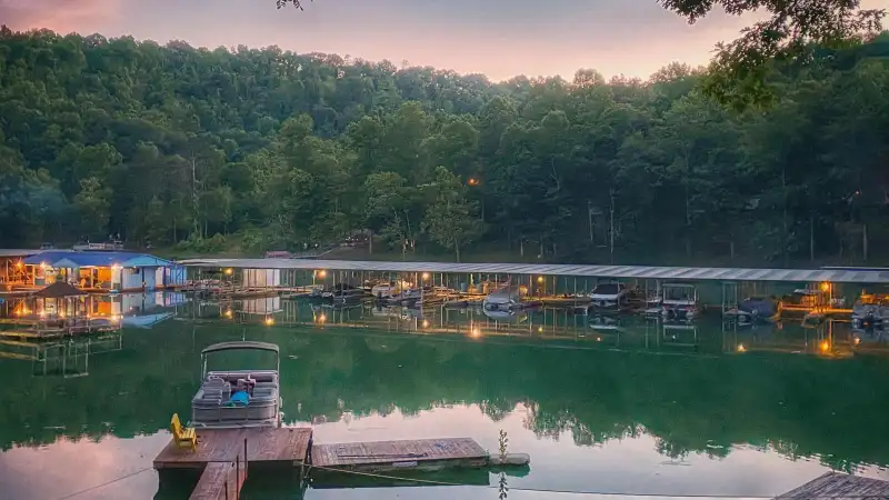 Peaceful lakeside view with boats docked and forested hills.